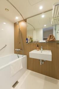 ein Badezimmer mit einem Waschbecken, einer Badewanne und einem Spiegel in der Unterkunft Tazawako Lake Resort & Onsen / Vacation STAY 78938 in Senboku