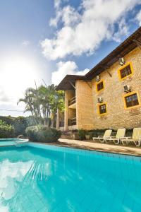 a house with a swimming pool next to a building at Pousada da Ladeira in Pipa