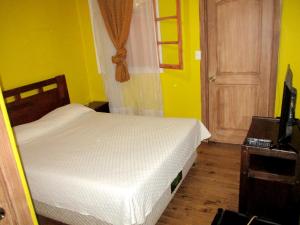 1 dormitorio con cama blanca y pared amarilla en Hotel Centro Sur - Colonial, en San Fernando