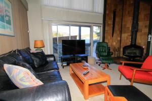 a living room with a black leather couch and a tv at Sierra Park Villas #24 in Mammoth Lakes