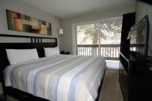 Un dormitorio con una cama y un balcón con televisión. en Sierra Park Villas #03, en Mammoth Lakes