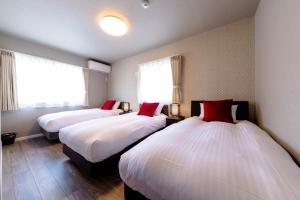 una camera d'albergo con due letti con cuscini rossi di Bon Moment A棟-紅葉館 a Fujikawaguchiko