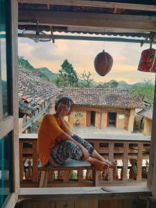 una persona sentada en un banco en un balcón en Homie homestay en Loung Co