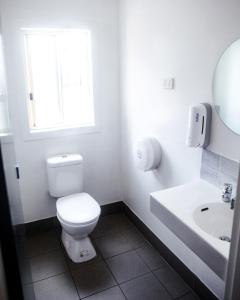 a white bathroom with a toilet and a sink at Budds In Surfers Backpackers in Gold Coast