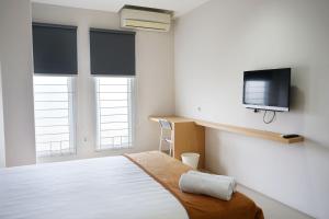 ein Schlafzimmer mit einem Bett und einem TV an der Wand in der Unterkunft UROOMS Senayan in Jakarta