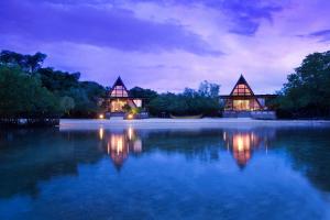 um par de casas na água à noite em Plataran Menjangan Resort and Spa - CHSE Certified em Banyuwedang