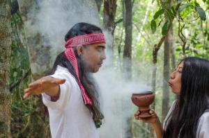a man and a woman standing in a forest with smoke at Rotamundos Mama Loomm in Puerto Morelos