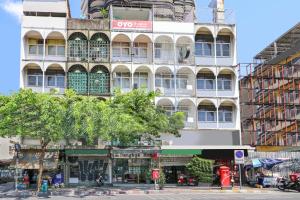 un edificio blanco alto con un árbol delante de él en OYO 688 Bangkok Hub Hostel, en Bangkok