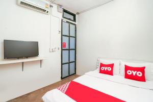 a bedroom with a tv and a bed with red pillows at OYO 688 Bangkok Hub Hostel in Bangkok