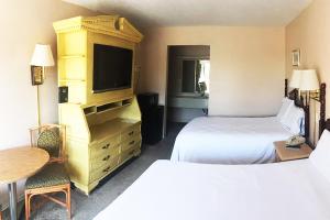 um quarto de hotel com duas camas e uma televisão em Micanopy Inn em Micanopy