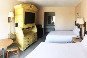 Habitación de hotel con 2 camas y TV en Micanopy Inn, en Micanopy