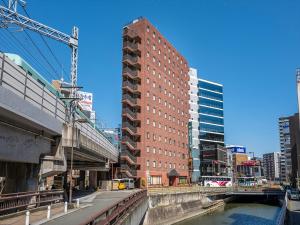 un edificio alto de ladrillo rojo junto a un río en Nishitetsu Inn Tenjin, en Fukuoka