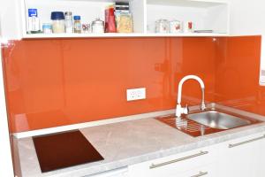 uma cozinha com um lavatório e uma parede laranja em Room & 4 Studios - Modern Comfy Central - FREE Netflix em Zagreb