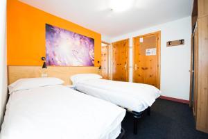 a hotel room with two beds and a television at Hotel Teola in Livigno