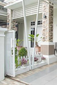 a porch with white chairs and plants on it at Huning House - 5 Bedrooms in Purwokerto