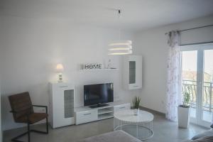 a white living room with a tv and a chair at Apartments Villa Lili in Crikvenica