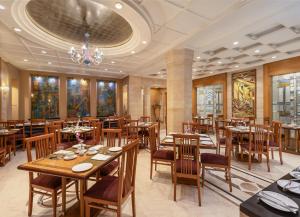 a restaurant with wooden tables and chairs and a chandelier at Sarovar Portico Kalupur Ahmedabad in Ahmedabad