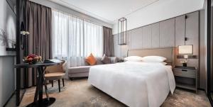 a hotel room with a large white bed and a table at Hotel Landmark Canton in Guangzhou