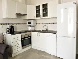 una cucina con armadi bianchi, lavandino e frigorifero di Apartament Fora Port a Fornells