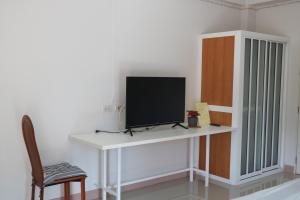 a tv sitting on a white desk with a chair at Prinya house ปริญญา เฮ้าส์ in Ban Huai Kapi