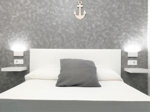 1 dormitorio con cama blanca y ancla en la pared en Apartament Fora Port, en Fornells