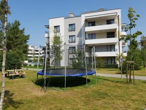 una cama elástica en un parque frente a un edificio en Fala Baltyku Apartament, en Ustronie Morskie