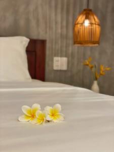 two frangipani flowers on a white bed at Okra Hoian in Hoi An