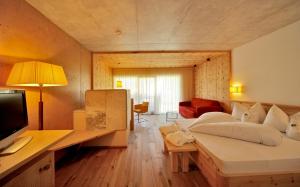 a bedroom with a bed and a desk with a television at Sporthotel Rasen in Rasùn di Sotto