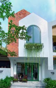 a white building with a green door and two benches at Okra Hoian in Hoi An