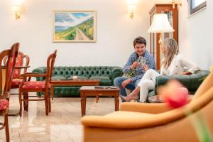 a man and woman sitting on a couch in a living room at Hotel Cvita in Split