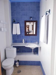 een blauw betegelde badkamer met een toilet en een wastafel bij Hospedería El Caravansar in Frigiliana