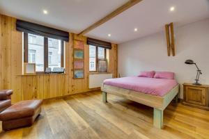 een slaapkamer met een roze bed en houten vloeren bij maison familiale près de bruxelles et paridaisia in Enghien