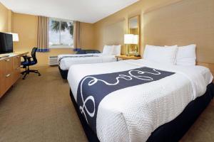 um quarto de hotel com duas camas e uma secretária em La Quinta by Wyndham Coral Springs South em Coral Springs