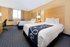 a hotel room with two beds and a desk at La Quinta by Wyndham Coral Springs South in Coral Springs