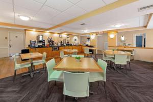 a dining room with tables and chairs and a kitchen at La Quinta by Wyndham Coral Springs South in Coral Springs