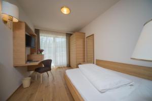 sypialnia z łóżkiem i biurkiem z krzesłem w obiekcie Park Hotel Bellevue w mieście Dobbiaco