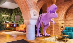 a purple dinosaur statue in a room with chairs at Bunk Hotel Amsterdam in Amsterdam