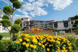 a park with yellow flowers in front of a building at Nevis Resort & Aqua Park - All Inclusive in Sunny Beach