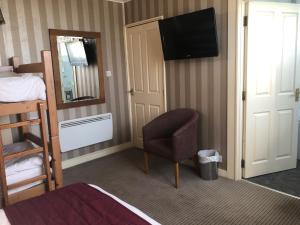 a bedroom with a bed and a chair and a television at The Dog & Partridge Country Inn in Ashbourne