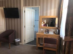 a hotel room with a desk and a mirror at The Dog & Partridge Country Inn in Ashbourne