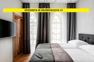 1 dormitorio con 1 cama y TV de pantalla plana en Piano Apartments, en Kaunas