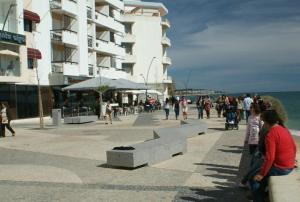 a group of people walking on a sidewalk near a building at Apartamento Urb. Vila Nova, Lote 5 in Armação de Pêra