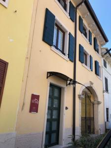 un edificio con ventanas con persianas azules y una puerta en La casa della Ada, en Castelnuovo del Garda