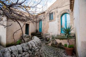 a stone house with blue windows and a stone wall at IL CORVO DI PIETRA in Scicli