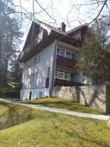 ein großes weißes Haus mit einer Steinmauer in der Unterkunft Studija GRaDO2 in Juodkrantė