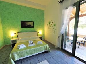 a bedroom with a bed with a green wall at Hotel Alba Chiara Sant'Andrea Salento in SantʼAndrea