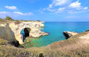 an arch in a rock formation in the ocean at Hotel Alba Chiara Sant'Andrea Salento in SantʼAndrea