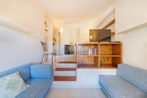een woonkamer met twee blauwe banken en een tv bij Ambra White in Li Valcaggi