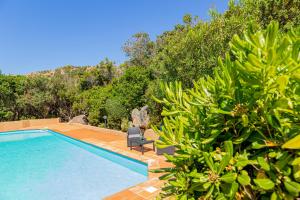 een zwembad met een stoel naast enkele bomen bij Ambra White in Li Valcaggi