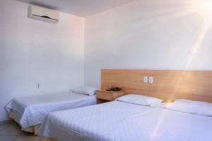2 camas en una habitación de hotel con sábanas blancas en Pioneiro Hotel, en Teixeira de Freitas